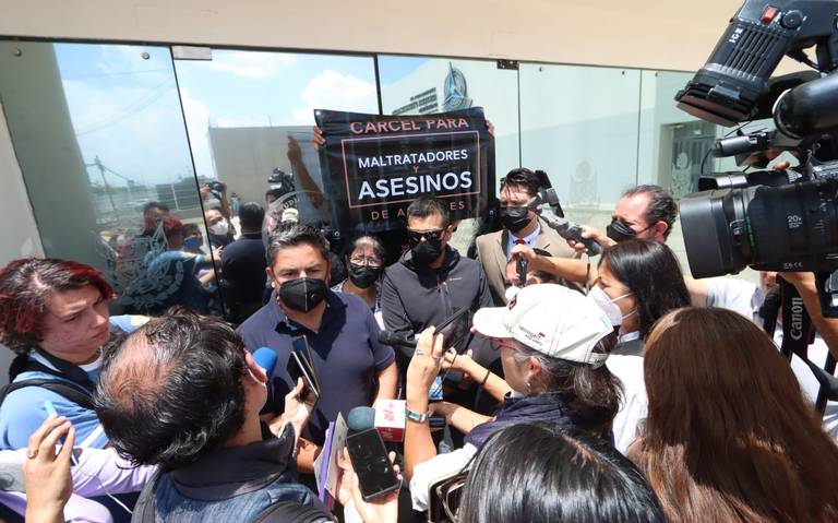 Personas reunidas en una conferencia de prensa. Se ven pancartas de manifestación