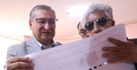 Hombre con discapacidad visual examinando plantilla con braille para la próximas elecciones en Ecuador