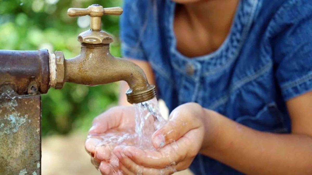 Niño tomando agua de una llave de agua.