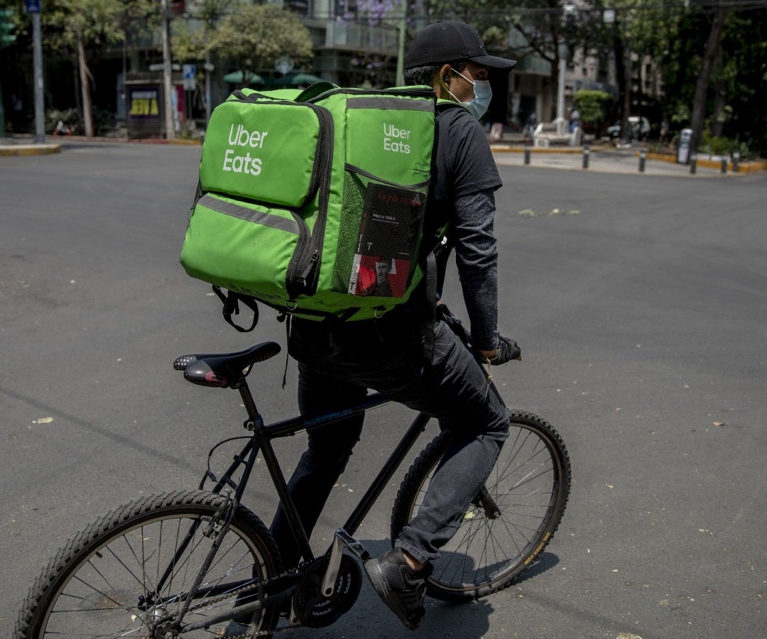 Hombre en bicicleta portando un bolso de Uber Eats