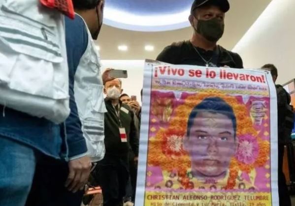 Hombre sostiene cartel con fotograf&iacute;a de joven