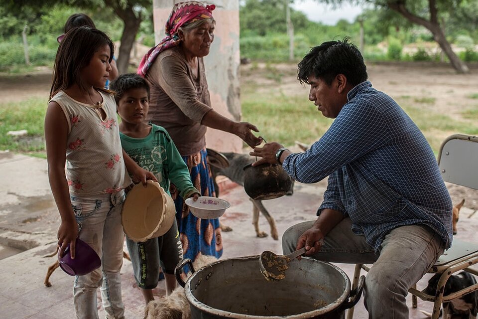 Dos niños y una adulta mayor recibiendo comida de un hombre