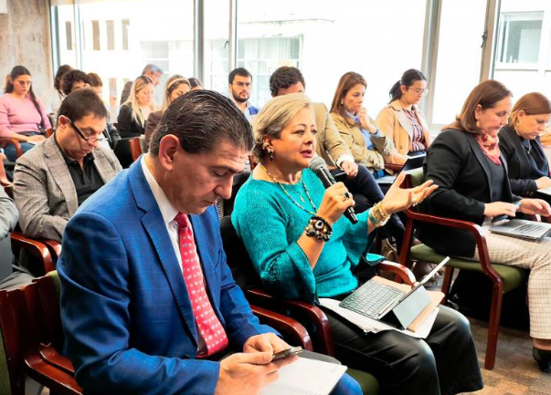 Público sentado, una mujer del público con un microfono esta habalndo.