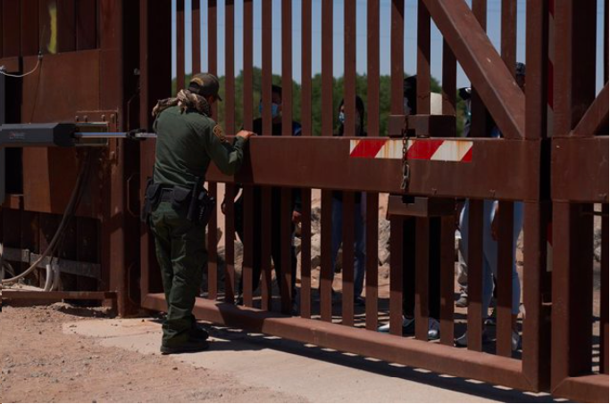Personas haciendo fila en frontera entre México y Estados Unidos.
