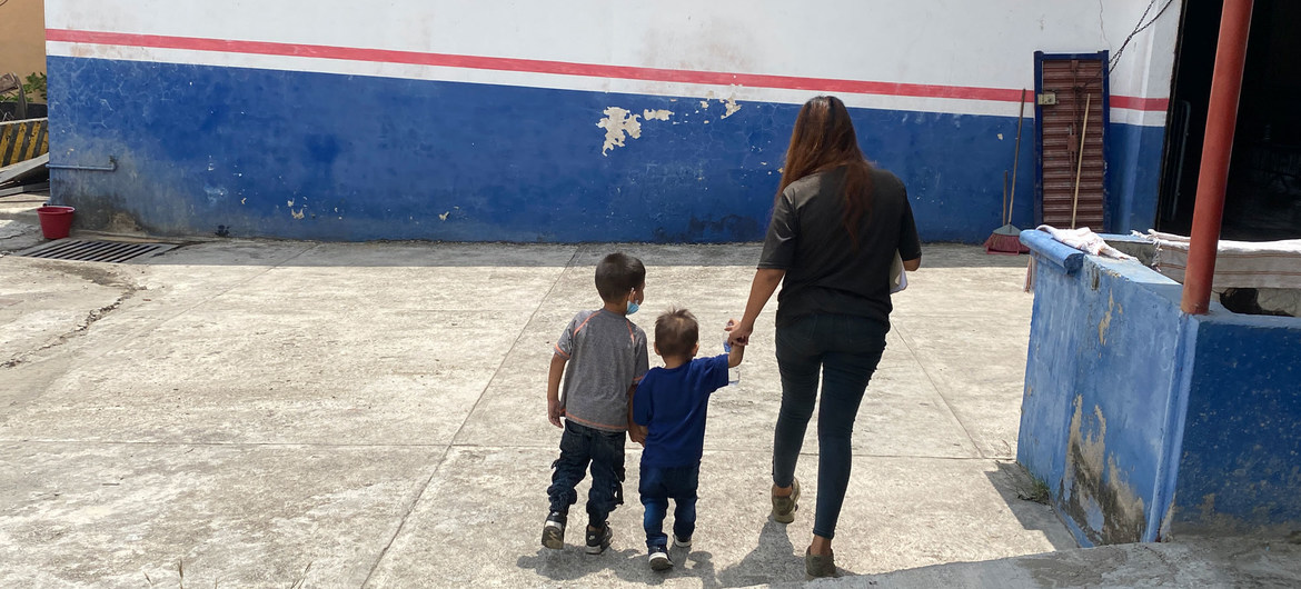 Mujer y dos ni&ntilde;os de espaldas en un patio.